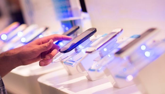 An undated image of a person testing smartphones. — Canva