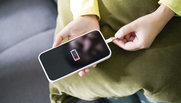 An undated image of a person connecting a phone with a charger. — Unsplash