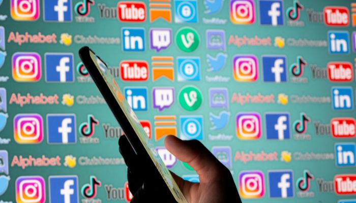 An image of a woman with a smartphone is seen in front of displayed social media logos in this illustration taken on May 25, 2021. — Reuters