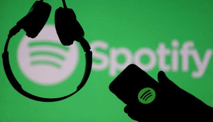 A smartphone and a headset are seen in front of a screen projection of Spotify logo, in this picture illustration taken April 1, 2018. — Reuters