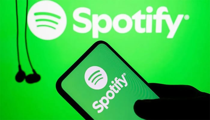 An undated image shows Spotify app displayed on a smartphone, with earphones and the Spotify logo in background. — Getty Images